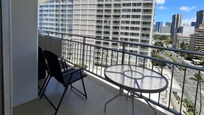 En balkon med et bord og stole, der udover byudsigter med moderne bygninger.