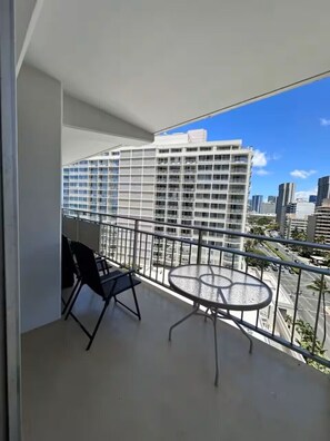 Ein Balkon mit Tisch und Stühlen mit Blick auf eine Stadtlandschaft und moderne Gebäude.