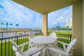 Ein Balkon mit Tisch und Stühlen, der Blick auf einen Strand und eine Straße freigibt.
