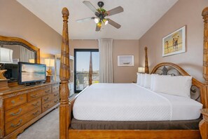 Une chambre d’hôtel avec un lit à baldaquin, un téléviseur posé sur une commode en bois et un balcon avec vue.