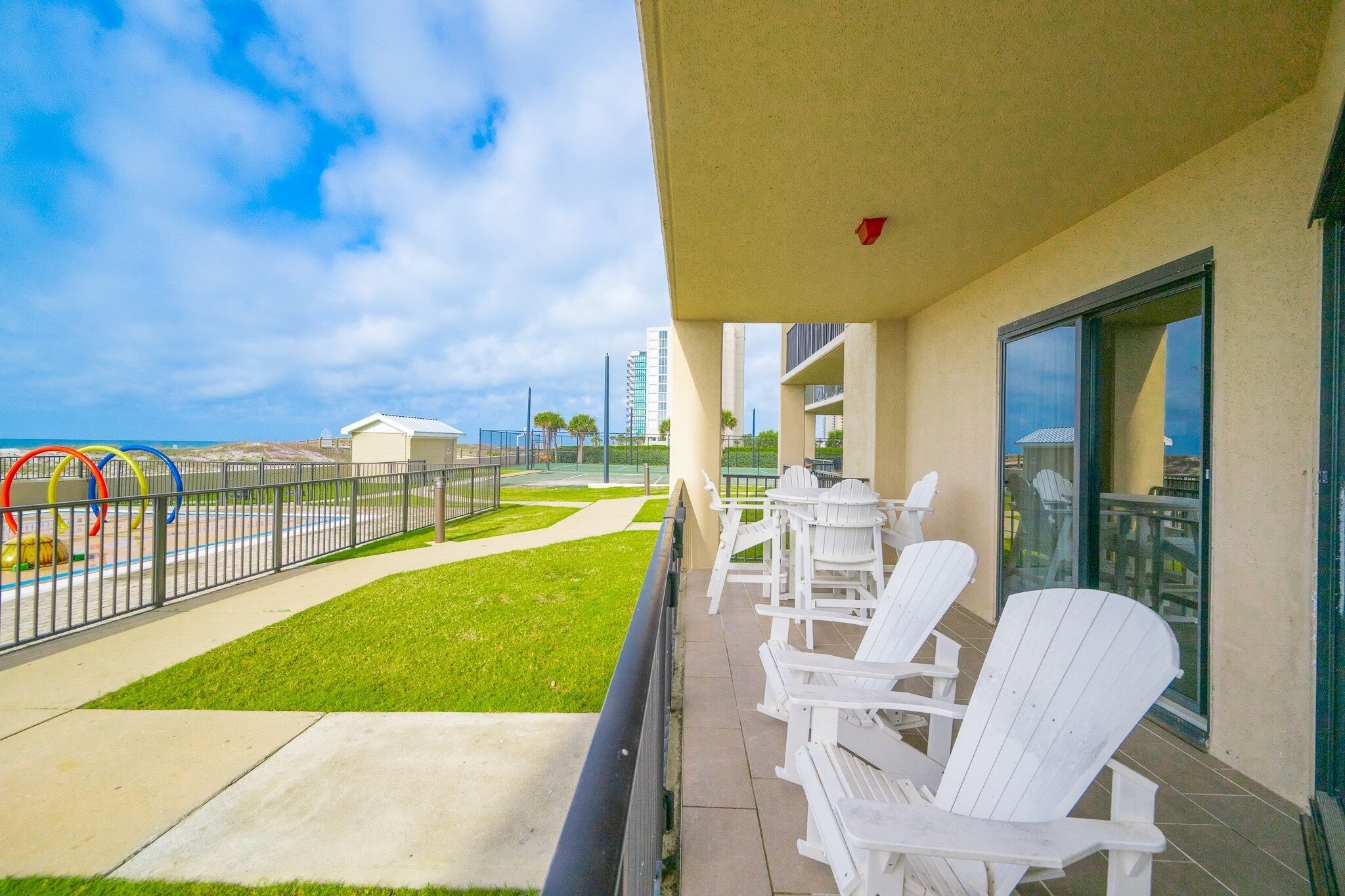 A balcony with white chairs and a view of the ocean.