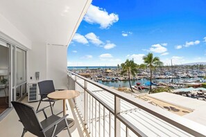 A balcony with a view of a marina and boats, a table, and two chairs. - Ilikai 1Bd 15th flr Ocean/Harbor Views-Steps to the beach! (Honolulu)