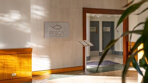 A reception area with a sign for 'PESCA Waikiki Beach' and a 'Fire Exit' sign. - Ilikai 1Bd 15th flr Ocean/Harbor Views-Steps to the beach! (Honolulu)
