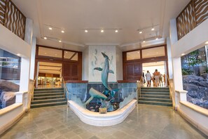 A lobby with a central sculpture of a whale and a staircase leading to upper floors. - Ilikai 1Bd 15th flr Ocean/Harbor Views-Steps to the beach! (Honolulu)