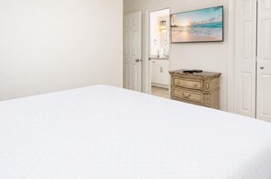 Una camera da letto con un letto, una cassettiera e un quadro raffigurante una spiaggia.