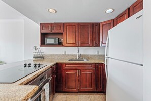 Eine Küche mit Holzausstattung, einer Mikrowelle, einem Kühlschrank und einer Arbeitsplatte aus Granit.
