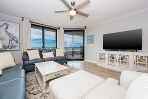 Un salon comprenant un canapé, une table basse et un téléviseur, avec un balcon et une vue sur l’océan.