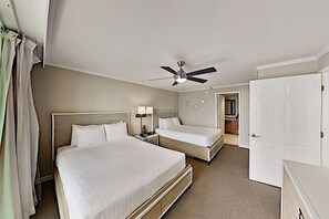 A hotel room with two beds, a ceiling fan, a desk with a lamp, and a door leading to a bathroom. - 1BR Ocean View Luana Waikiki w/FREE PARKING! (Honolulu)