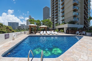 A swimming pool with lounge chairs and a gazebo, surrounded by high-rise buildings. - 1BR Ocean View Luana Waikiki w/FREE PARKING! (Honolulu)