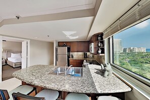 A modern kitchen with granite countertops, stainless steel appliances, and a view of a cityscape. - 1BR Ocean View Luana Waikiki w/FREE PARKING! (Honolulu)