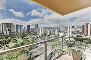 Stadsgezicht met hoge gebouwen, een heldere lucht en een balkon met uitzicht over de stad.