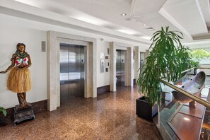 A lobby with a statue, elevators, and a large potted plant. - 1BR Ocean View Luana Waikiki w/FREE PARKING! (Honolulu)