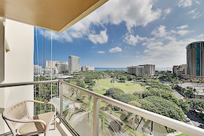 A balcony with a view of a cityscape, including high-rise buildings and a park. - 1BR Ocean View Luana Waikiki w/FREE PARKING! (Honolulu)