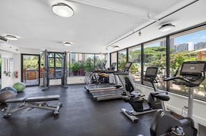 A gym with cardio machines, free weights, and a view of the city. - 1BR Ocean View Luana Waikiki w/FREE PARKING! (Honolulu)