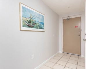 A hallway with a framed painting of a boat on the wall, a door with a lock, and a light fixture on the ceiling. - Phoenix X 913 3 Bedroom Condo (Orange Beach)