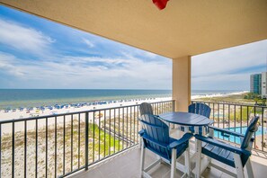 Un balcon avec vue sur une plage et l’océan, comprenant une table et des chaises.