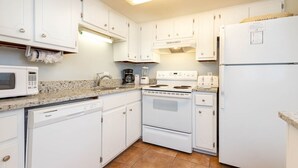 A kitchen with white cabinets, a microwave, a dishwasher, a stove, and a refrigerator. - Island Winds East 107 2 Bedroom Condo (Gulf Shores)