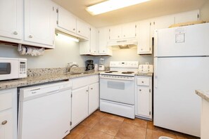 A kitchen with white cabinets, a microwave, a dishwasher, a stove, and a refrigerator. - Island Winds East 107 2 Bedroom Condo (Gulf Shores)