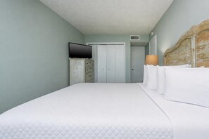 A hotel room with a bed, a television, a wardrobe, and a door. - Island Winds East 107 2 Bedroom Condo (Gulf Shores)