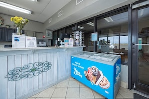 A reception area with a counter, computer, and a large ice cream display. - Island Winds East 107 2 Bedroom Condo (Gulf Shores)