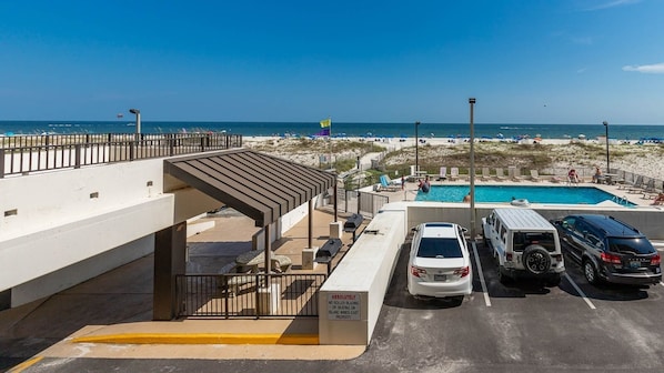 A parking area with a pool, beach, and ocean view. - Island Winds East 107 2 Bedroom Condo (Gulf Shores)