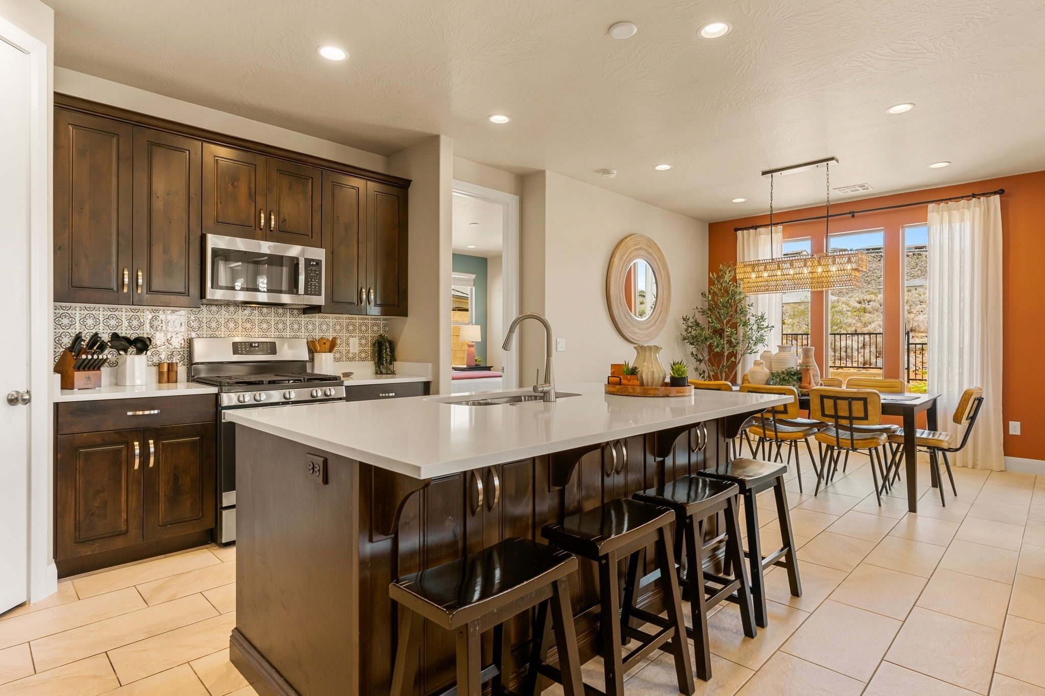 A modern kitchen with dark wood cabinets, stainless steel appliances, and a central island with bar stools.