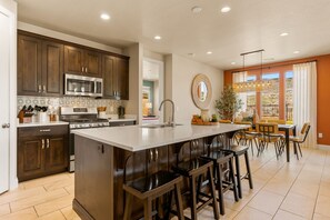 A modern kitchen with dark wood cabinets, stainless steel appliances, and a central island with bar stools. - Papa Oak's Casa 5 Bedroom Home (Washington)
