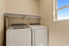 A laundry room with a washer and dryer, a window, and a shelf above the washer. - Papa Oak's Casa 5 Bedroom Home (Washington)