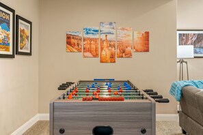 Una stanza con un tavolo da calcio, un divano e una parete con quadri.
