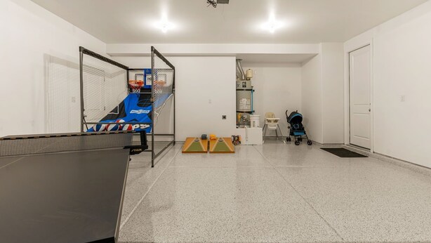 Una habitación amplia con mesa de ping pong, aro de baloncesto y un cochecito de bebé.