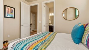 Un dormitorio con cama, un espejo y una puerta que da a otra habitación.