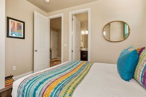 A bedroom with a bed, a mirror, and a door leading to another room. - Papa Oak's Casa 5 Bedroom Home (Washington)