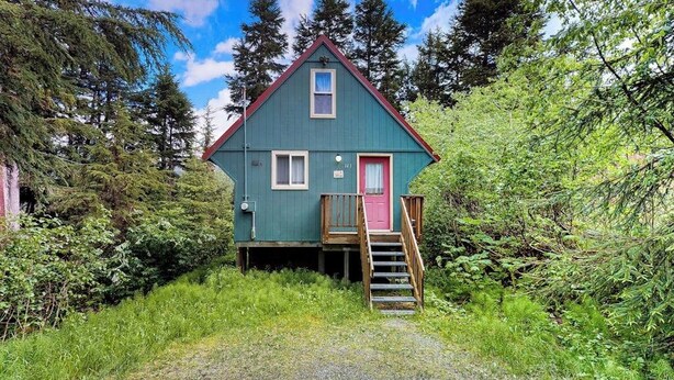 A small, single-story cabin with a red door and a wooden staircase leading to a deck. - Quiet A-frame Tucked Off the Road in Girdwood (Girdwood)