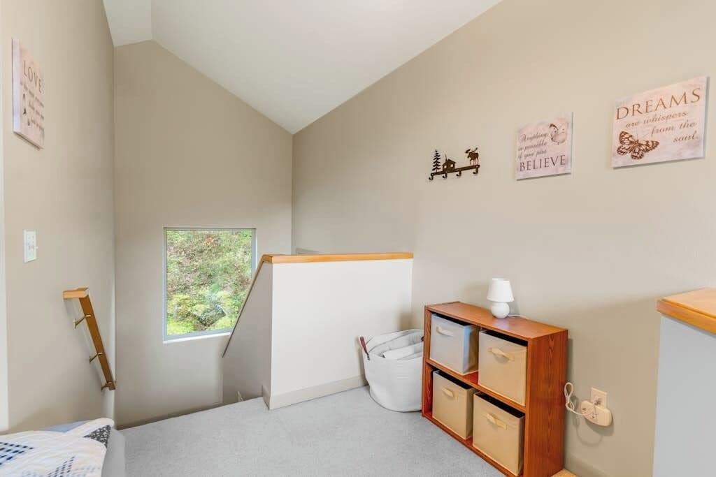 Un dormitorio con literas, una ventana que da a zonas verdes, una mesita de noche con lámpara y decoración mural inspiradora.