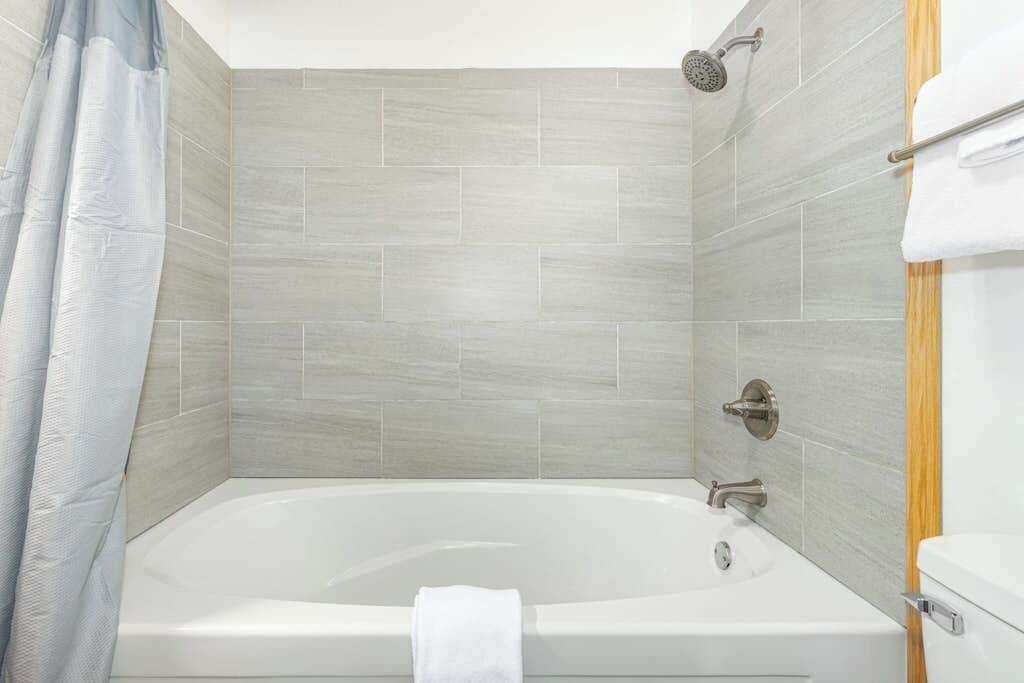Ein modernes Badezimmer mit einer freistehenden Badewanne, einer Duschbrause und einem Handtuchhalter.