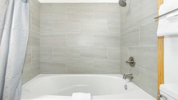 Ein modernes Badezimmer mit einer freistehenden Badewanne, einer Duschbrause und einem Handtuchhalter.