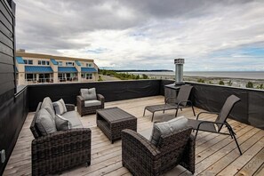 A covered outdoor seating area with wicker furniture and a view of a body of water.
