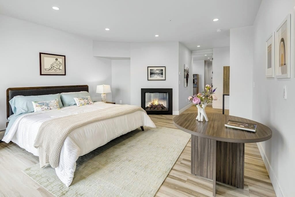 A bedroom with a bed, bedside table, and a fireplace.