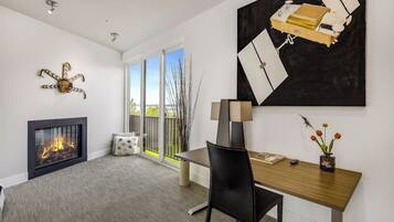 A modern living room with a fireplace, a dining area, and a large abstract painting.