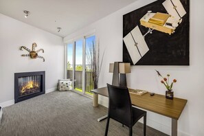 A modern living room with a fireplace, a dining area, and a large abstract painting.