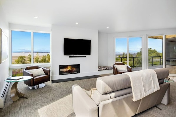A modern living room with a fireplace, a flat-screen TV, and a sofa. - Two-story Loft Villa w/ Rooftop Hot Tub & Inlet Views (Anchorage)