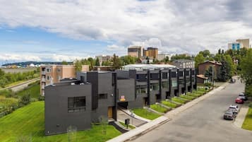A modern building with a flat roof, large windows, and a parking lot with cars.