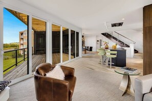 A spacious living area with a balcony, a staircase, and a dining area.