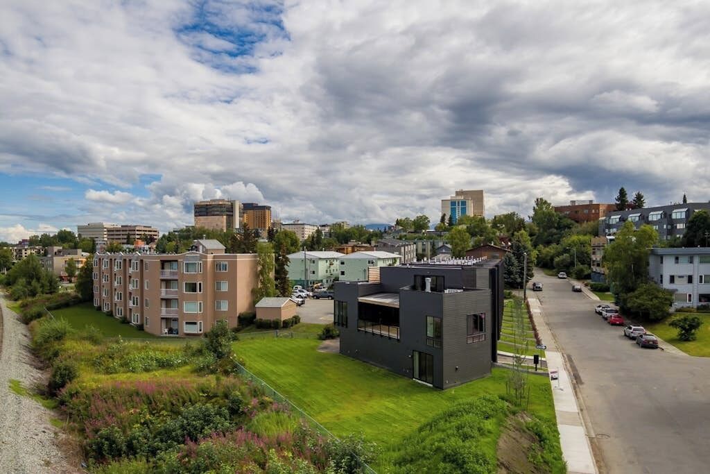 A residential area with modern buildings, a well-maintained lawn, and a clear road.