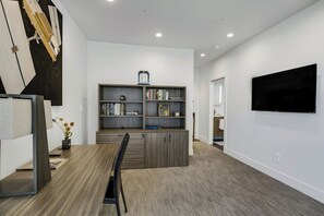 A modern living room with a dining area, a bookshelf, a flat-screen TV mounted on the wall, and a large mirror. - Two-story Loft Villa w/ Rooftop Hot Tub & Inlet Views (Anchorage)