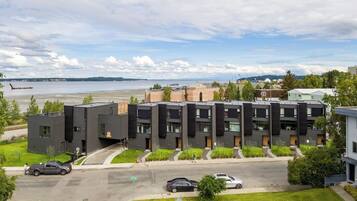 A modern apartment building with a parking lot and a view of the water.