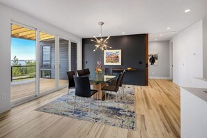 A modern dining area with a glass table, black chairs, and a patterned rug.
