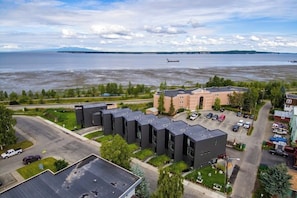 A residential area with modern buildings, a parking lot, and a view of a large body of water with a distant airplane.