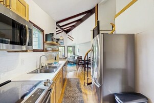 Una cocina compacta con electrodomésticos modernos, horno integrado y refrigerador de acero inoxidable.