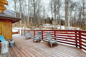 Une terrasse en bois avec des fauteuils Adirondack et un chalet en bois.